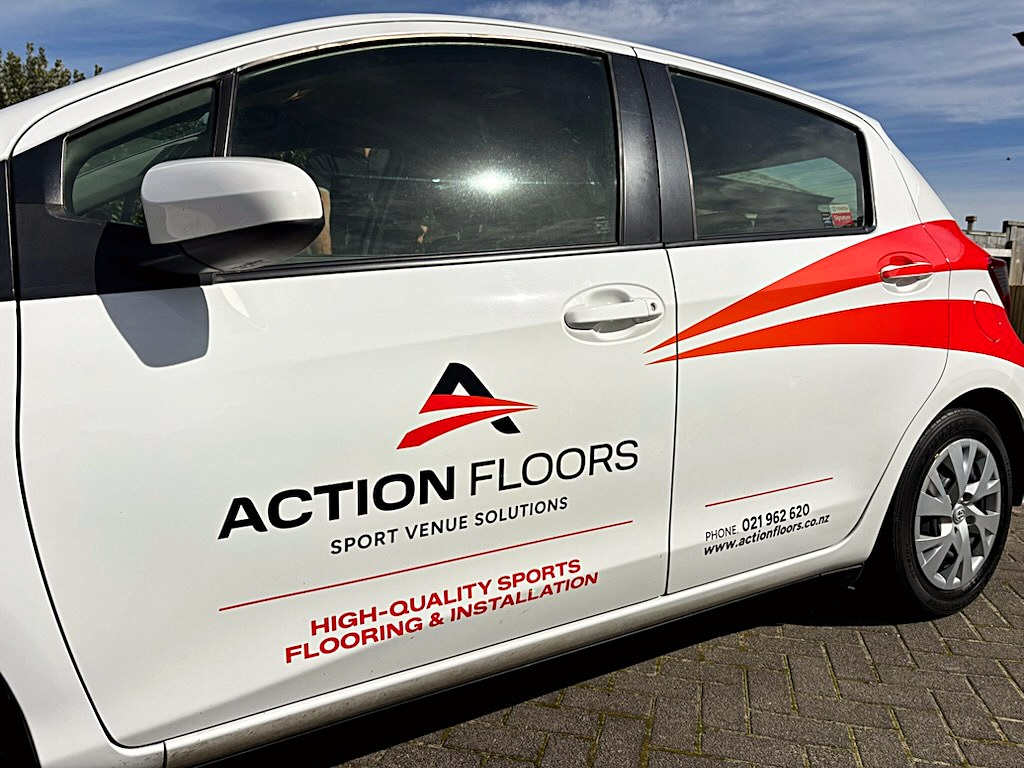 Action Floors branded vehicle — a white hatchback carrying the Action Floors logo, red swoosh graphics and contact details along the driver's door