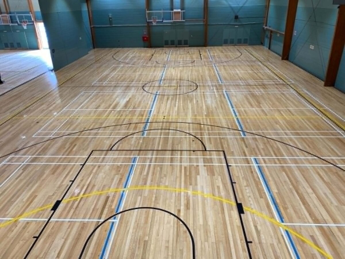 Re-sanded maple timber court at Stanmore Bay Recreation Centre with black, blue, yellow and white line marking against teal painted walls