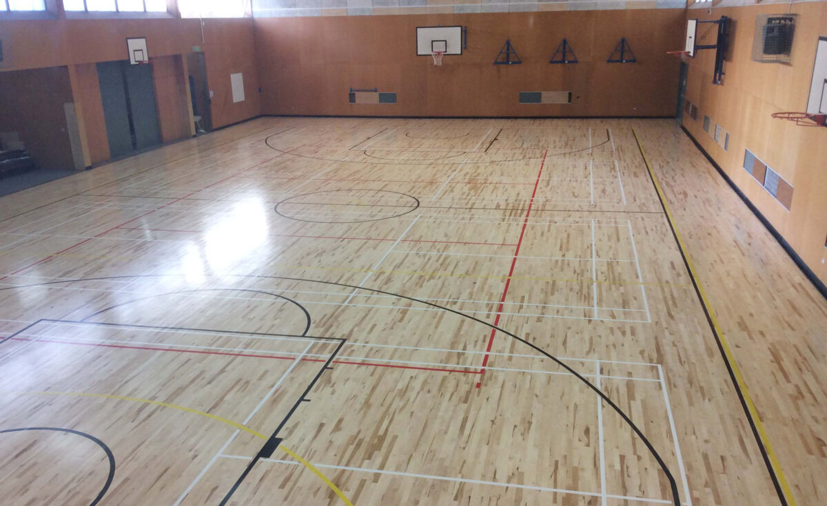 Refinished Action Pro Air maple sprung timber court at Tawa College in Wellington, warm blond boards with multi-colour line marking