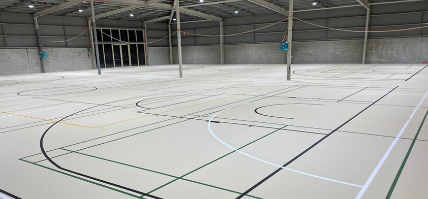 Synthetic Herculan roller hockey court at Wanaka Youth & Community Centre, pale grey surface with multi-sport line marking in an open steel-framed hall